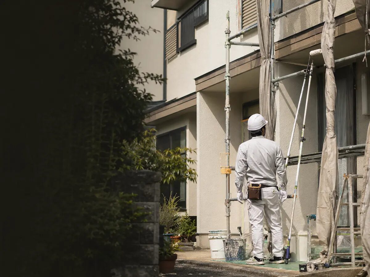 足場のある建物で作業する塗装職人